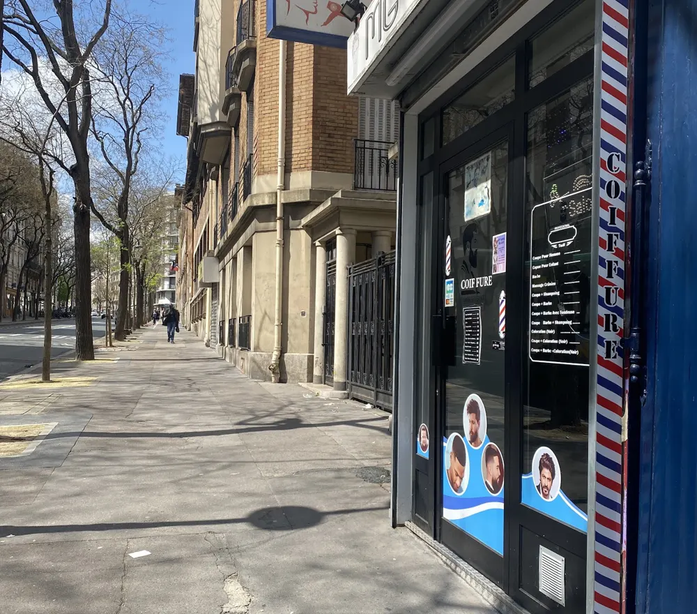 Le trottoir ensoleillé de la rue d'Alésia et la devanture du salon.